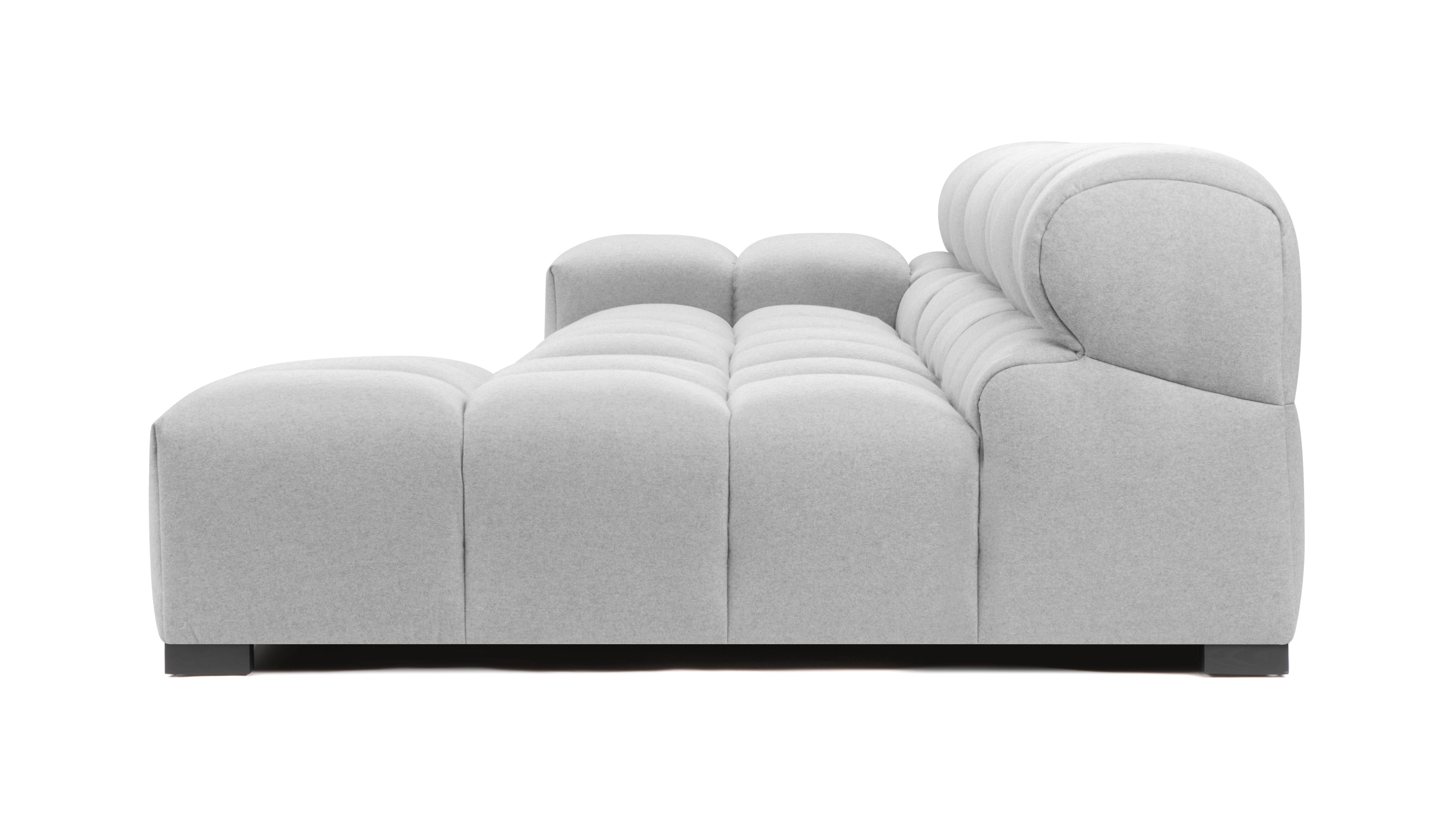 Light gray tufted sectional couch in a spacious living room, offering plush seating and sophisticated style.