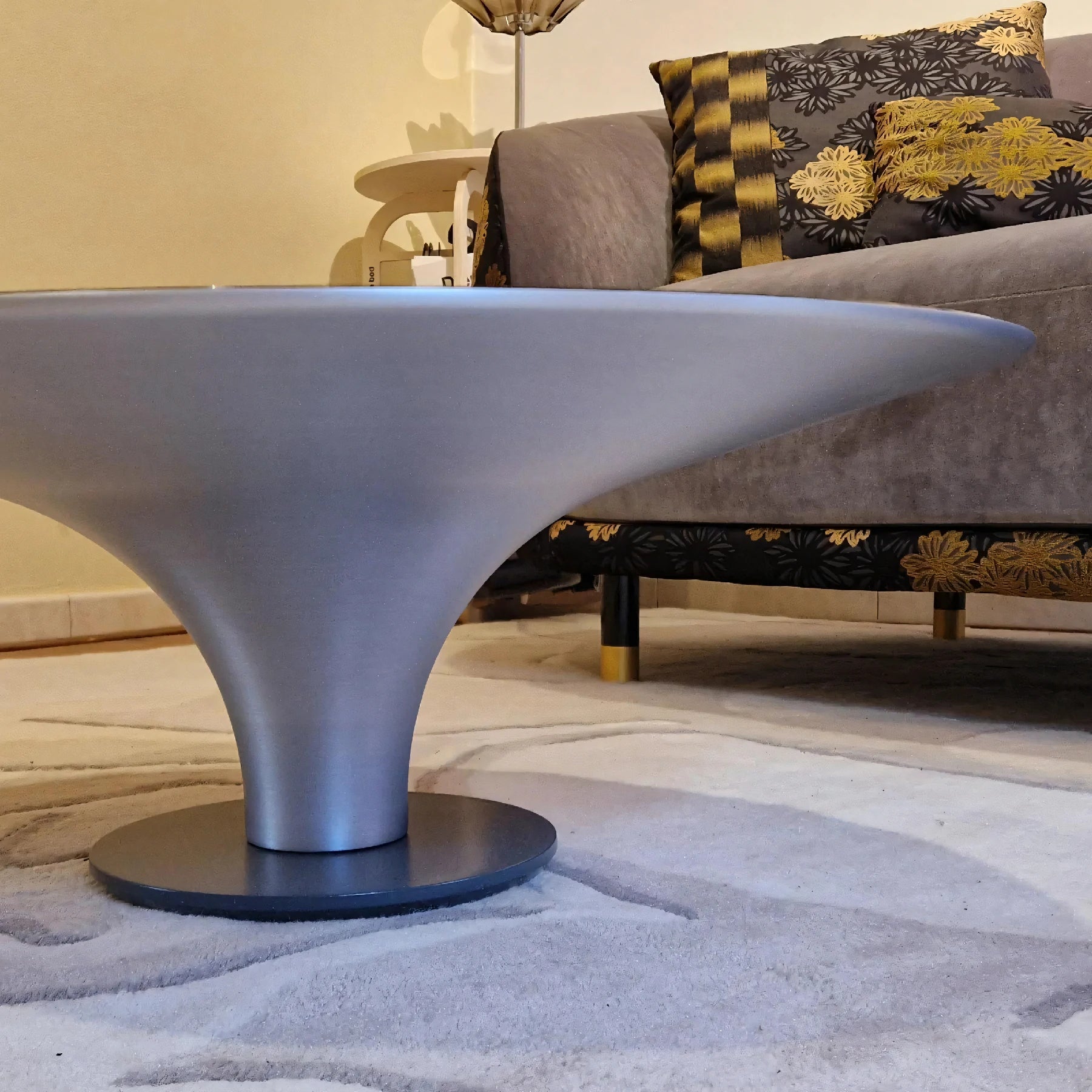 The Ovni Uovo coffee table offers sophistication with its aluminum base and clear glass top, perfect for stylish living rooms.